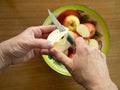 Woman Coring an Apple with a Tin Bowl with Apples in the Background