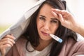 Woman with coronavirus suffers high fevers holding a blanket over her, measuring body temperature Royalty Free Stock Photo