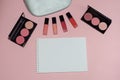 Woman cosmetic bag, make up beauty products on pink background, notebook. Red and pink lipstick. Makeup brushes and rouge palettes Royalty Free Stock Photo