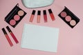 Woman cosmetic bag, make up beauty products on pink background, notebook. Red and pink lipstick. Makeup brushes and rouge palettes Royalty Free Stock Photo