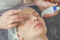 Woman in cosmetic cap on couch at spa salon. Preparation of facial skin for cosmetic procedures, cleaning, massage, relaxation