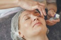 Woman in cosmetic cap on couch at spa salon. Preparation of facial skin for cosmetic procedures, cleaning, massage, relaxation