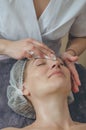 Woman in cosmetic cap on couch at spa salon. Preparation of facial skin for cosmetic procedures, cleaning, massage, relaxation