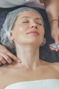 Woman in cosmetic cap on couch at spa salon. Preparation of facial skin for cosmetic procedures, cleaning, massage, relaxation