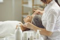 Woman cosmetologist cleaning womans face with cotton pads after or before skincare procedure