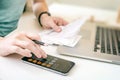 Woman making audit of household spendings at home, using calculator