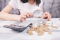 Woman counts money with calculator and looks with magnifying glass