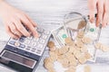 Woman counts money with calculator and looks with magnifying glass