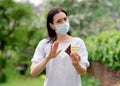 Woman in cover face mask holding chocolate and not supposing to eat it