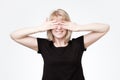 Woman covering eyes with hands and smiling broadly, being intrigued while waiting for surprise