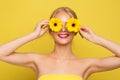 Woman covering Eyes with Yellow Flowers. Happy Smiling Model with Gerbera Floral Sun Glasses over isolated Orange background Royalty Free Stock Photo