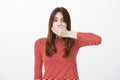 Woman covering mouth not to tell secret of friend. Studio shot of shocked and amazed caucasian female student with red