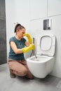 woman covering nose to avoid bad smell while cleaning a smelly toilet bowl Royalty Free Stock Photo