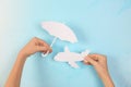 Woman covering paper plane with umbrella cutout on color background, closeup. Royalty Free Stock Photo