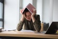 Woman covers head with book feeling tired and powerless