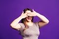 Woman covers her eyes, plus size model on purple background