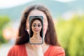 A woman covers her face with a smartphone with a cartoon portrait of a woman. The concept of hiding identity and fake pages in
