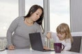 A woman covers the keyboard on a laptop with her hand from a small child. Concept: home appliances are not toys for children, Royalty Free Stock Photo