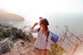 Woman in a cowboy hat posing. Sea and mountains on background. Bay with ships and the beach. Backpack. Touristic foam mat. Active Royalty Free Stock Photo