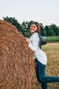 Woman in cowboy hat staying near a straw bale. Summer, beauty, fashion, glamour, lifestyle concept. Cottagecore farmcore Royalty Free Stock Photo