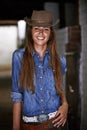 Woman or cowgirl, happy and portrait in stable for work or rodeo in Texas, western and culture for farming. Female
