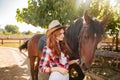 Woman cowgirl standing and taking care of horse in village Royalty Free Stock Photo