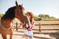 Woman cowgirl standing and taking care of horse in village Royalty Free Stock Photo