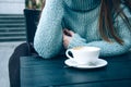 Woman in a cozy blue sweater drinking coffee in a street cafe Royalty Free Stock Photo