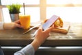 Woman in a cozy cafe near a large window sitting at the table and lead the conversation on social networks with your frie