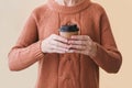 Woman in cozy warm orange sweater holding paper cup of coffee. Royalty Free Stock Photo