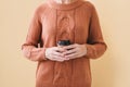 Woman in cozy warm orange sweater holding paper cup of coffee. Royalty Free Stock Photo