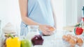 Woman cracking an egg into a bowl with standing by in kitchen. Royalty Free Stock Photo