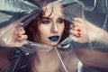 Woman with creative eye makeup peering cellophane