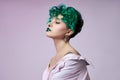 Woman with creative green coloring hair and makeup, toxic strands of hair. Bright color curly hair on the girl head, professional