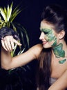 Woman with creative make up like snake with rat in her hands