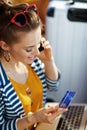 Woman with credit card using cell phone to pay for hotel room Royalty Free Stock Photo