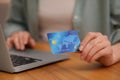 Woman with credit card using laptop for online shopping at wooden table, closeup Royalty Free Stock Photo