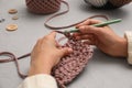 Woman crocheting with threads at grey table, closeup. Engaging hobby Royalty Free Stock Photo