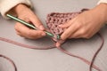 Woman crocheting with threads at grey table, closeup. Engaging hobby Royalty Free Stock Photo