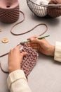 Woman crocheting with threads at grey table, closeup. Engaging hobby Royalty Free Stock Photo