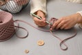 Woman crocheting with threads at grey table, closeup. Engaging hobby Royalty Free Stock Photo