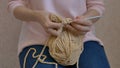 Woman crochets with beige yarn on knees, showcasing hobby. Crocheting as a hobby highlighted, ball of threads beside Royalty Free Stock Photo