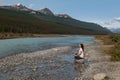 Woman crossed legs doing yoga and relaxing along the Athabasca River in Jasper National Park, Alberta, Canada Royalty Free Stock Photo