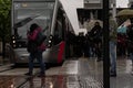 woman crosses in front of the tram while it is stopped.