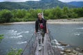 Woman crosses a mountain river over wooden bridge Royalty Free Stock Photo