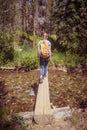 Woman crossing a stream in a forest in Rocky Mountain National Park Royalty Free Stock Photo