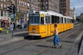 Woman crossing the street in front of a yellow streetcar