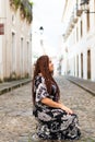 A woman crouched down on a cobbled street