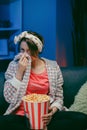 Young woman cry while watching a very moving movie with popcorn at night Royalty Free Stock Photo