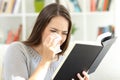 Woman crying while is reading a paper book at home